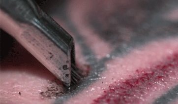 Введение игл под кожу при выполнении тату